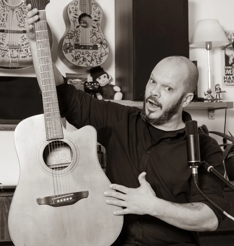 Seb, guitare à la main, dans son espace de musique